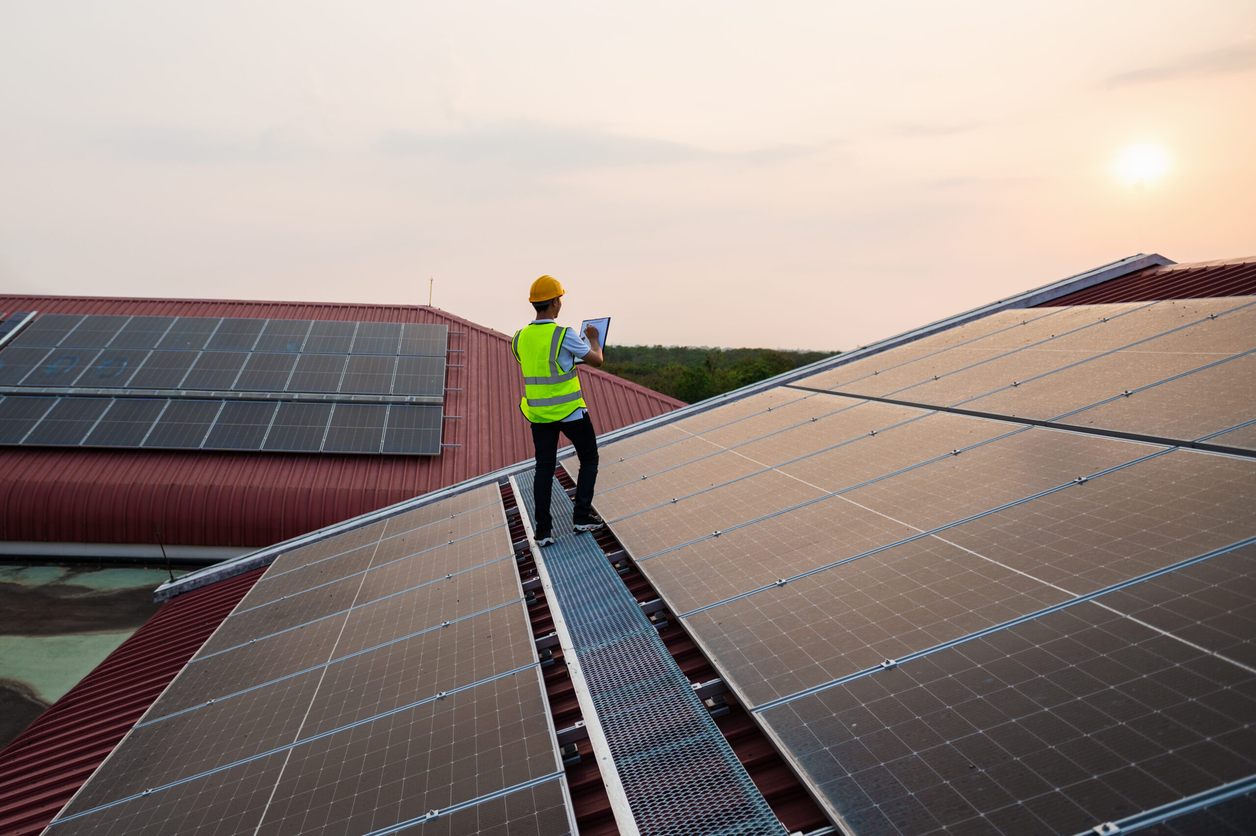 man in a yellow vest is walking on a metal walkway above a solar